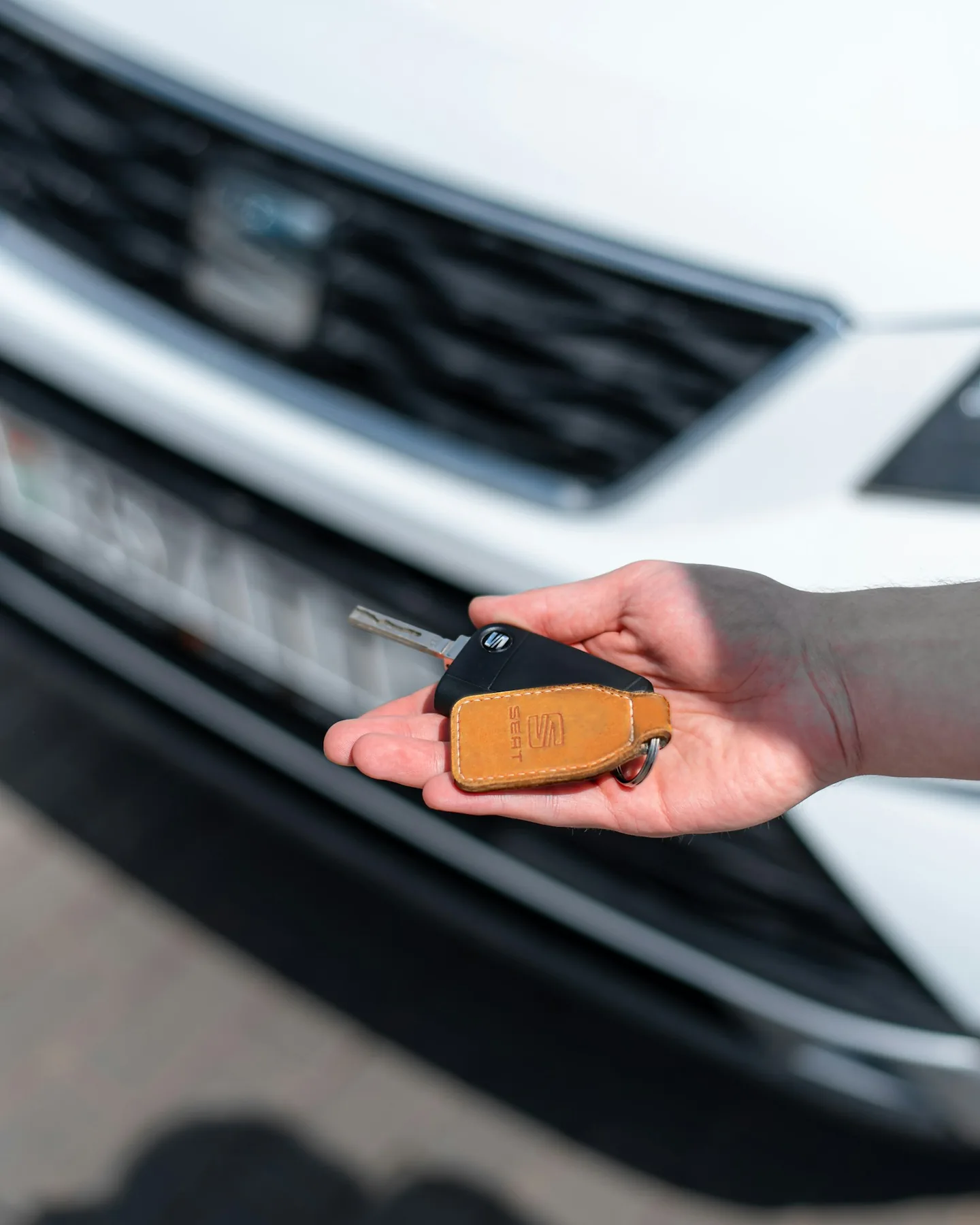 A vehicle key presented in front of a car