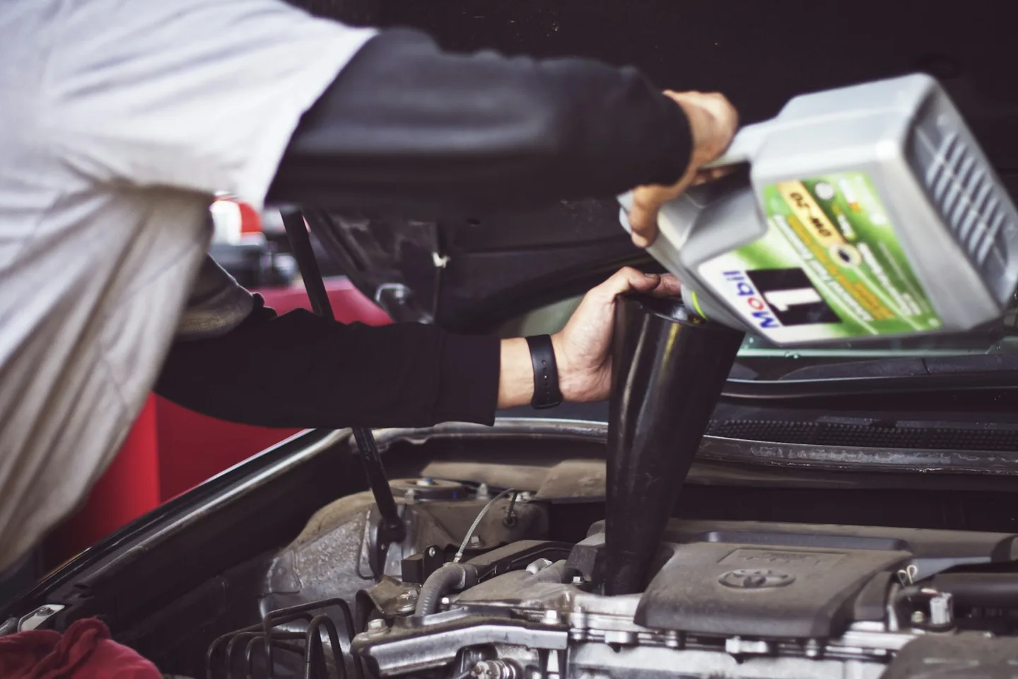 Mechanic adding motor oil to an engine